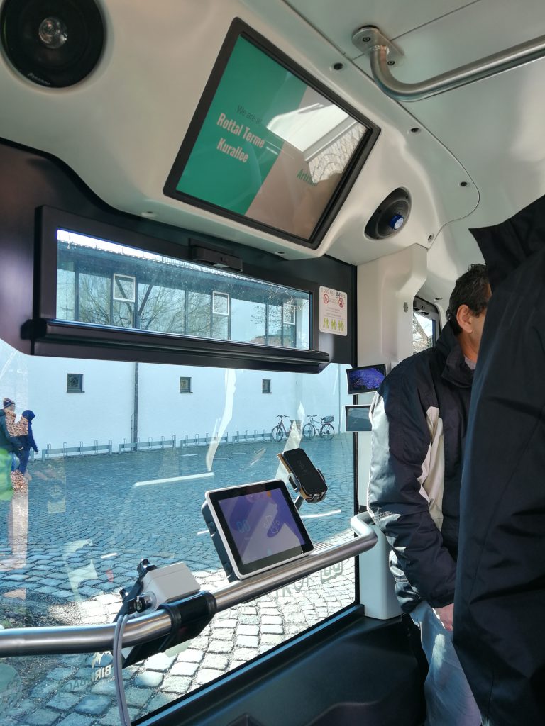 Im autonom fahrenden Kleinbus hängt ein Bildschirm, der die derzeitige und nächste Haltestelle anzeigt.
