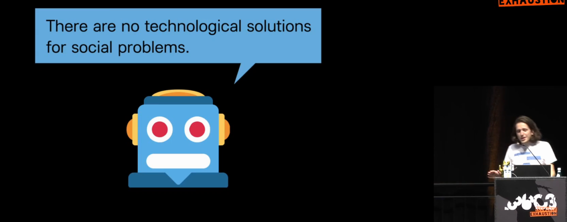 Ein Bot mit der Sprechblase: "There are no technological solutions for social problems.", daneben der Vortragende