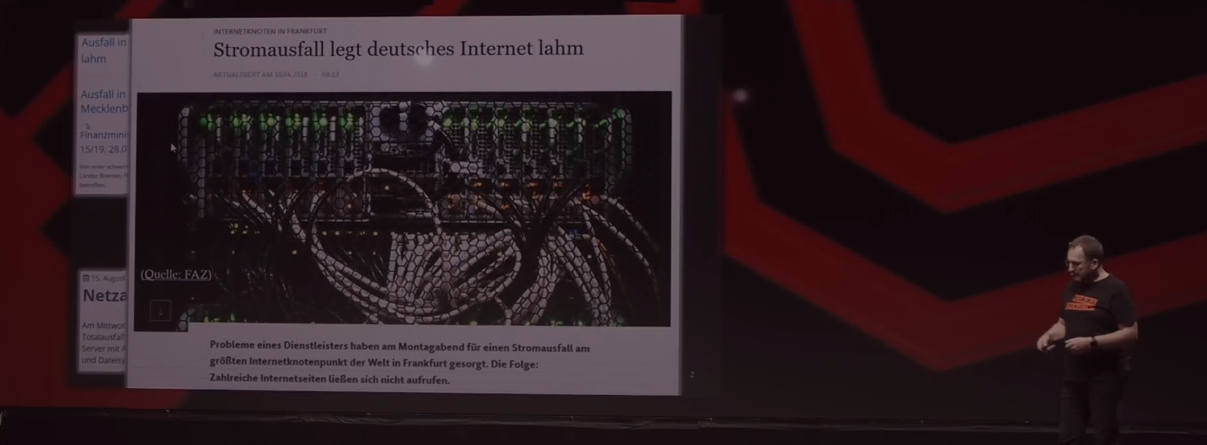 Leinwand mit Zeitungsausschnitt "Stromausfall legt deutsches Internet lahm", daneben der Vortragende